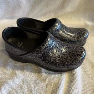 Dansko Professional tooled leather clogs featuring an intricate floral pattern.